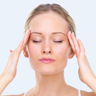 Close-up portrait of a young beautiful girl massaging forehead